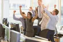 Exuberant Business People Cheering With Arms Raised In Office