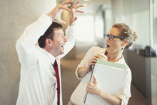 Businessman Making Snarling Gesture At Terrified Businesswoman