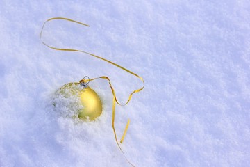 Wall Mural - The Golden Christmas ball is forgotten and lies on the snow. Concept of completion or end of winter holidays.