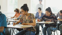 College Students Taking Test At Desks In Classroom