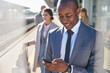 © Chris Ryan/Caia Image - Businessman texting with cell phone on train station platform