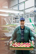 © Agnieszka Olek/Caia Image - Portrait smiling worker carrying box of apples in food processing plant