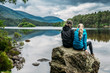 © Anna Wiewiora/Caia Image - Couple sitting on rock looking at tranquil lake, Loch an Eilein, Scotland