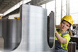 © Lukasz Olek/Caia Image - Female steel worker examining steel part in factory