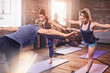 © Trevor Adeline/Caia Image - Women practicing yoga warrior 3 pose in exercise class gym studio