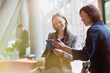 © Tom Merton/Caia Image - Businesswomen drinking coffee and using digital tablet in office lobby