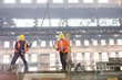 © Rafal Rodzoch/Caia Image - Steel workers with crane hooks in factory
