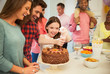 © Robert Daly/Caia Image - Smiling family icing chocolate cake in kitchen