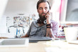 © Rafal Rodzoch/Caia Image - Pensive design professional headphones talking on cell phone at desk
