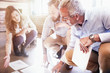 © Trevor Adeline/Caia Image - Business people reviewing discussing paperwork on sunny office floor