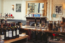 Wine Bottles And Tap Handles Behind Bar In Empty Pub