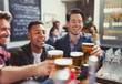 © Paul Bradbury/Caia Image - Men friends toasting beer glasses at bar