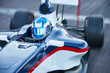 © Chris Ryan/Caia Image - Formula one race car driver in helmet on sports track