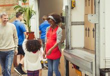 Multi-ethnic Young Family Unloading Moving Van Outside New House