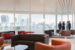 © Martin Barraud/Caia Image - Business people talking at window in urban highrise office lounge city view