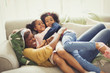 © Paul Bradbury/Caia Image - Playful mother and daughters cuddling on sofa
