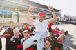 © Sam Edwards/Caia Image - Formula one racing team carrying driver on shoulders, celebrating victory on sports track