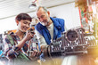 © Agnieszka Olek/Caia Image - Male and female motorcycle mechanics repairing engine in workshop