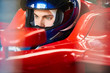 © Chris Ryan/Caia Image - Close up focused formula one driver wearing helmet in race car