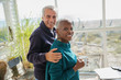 © Sam Edwards/Caia Image - Portrait smiling senior couple hugging drinking coffee on sunny beach house sun porch