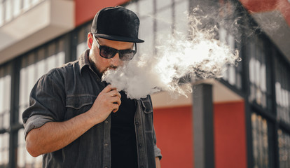 Young handsome man smoke with vape in urban location