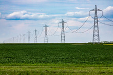 A Wide Angle View Of Electricity Pylons With Miles Of Overhead Power Cables Covering Many Acres Of Rural Farmland, Disappearing Into Distant Horizon