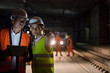 © Agnieszka Olek/Caia Image - Foreman engineer digital tablet talking on dark tracks at underground construction site