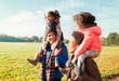© Robert Daly/Caia Image - Parents carrying daughters on shoulders in sunny autumn park
