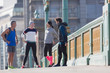 © Martin Barraud/Caia Image - Runners talking and stretching on sunny urban sidewalk