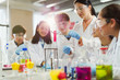© Robert Daly/Caia Image - Female teacher and students conducting scientific experiment, watching liquid in test tube in laboratory classroom