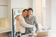 © Tom Merton/Caia Image - Portrait affectionate male gay couple hugging at laptop in kitchen