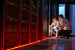 © Rafal Rodzoch/Caia Image - IT technicians talking at glowing panel in dark server room