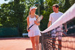 © Chris Ryan/Caia Image - Smiling male female tennis players talking at tennis net on sunny clay tennis court
