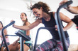 © Caiaimage/Sam Edwards/Caia Image - Smiling, playful young woman using elliptical bike in gym