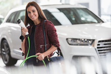 Portrait Smiling, Confident Woman Holding Hybrid Charging Cable In Car Dealership Showroom