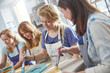 © Agnieszka Olek/Caia Image - Female artists painting picture frames in art class workshop