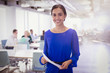 © Sam Edwards/Caia Image - Portrait smiling businesswoman with paperwork in office