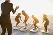 © Sam Edwards/Caia Image - Surfer instructor teaching family on surfboards surfing on sunny summer sunset beach