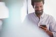 © Sam Edwards/Caia Image - Smiling man texting with cell phone
