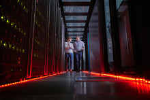 IT Technicians Talking And Walking In Dark Server Room