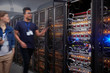 © Rafal Rodzoch/Caia Image - IT technicians walking along panels in server room