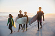 © Sam Edwards/Caia Image - Family surfers carrying surfboards on summer sunset beach