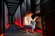 © Rafal Rodzoch/Caia Image - Female IT technician examining panel in dark server room