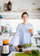 © Sam Edwards/Caia Image - Portrait smiling, confident brunette woman drinking healthy carrot juice at blender in kitchen
