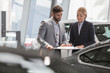 © Martin Barraud/Caia Image - Car salesman female customer reviewing financial contract paperwork in car dealership showroom