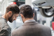 © Martin Barraud/Caia Image - Male mechanic and customer talking, looking down in auto repair shop