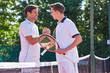 © Chris Ryan/Caia Image - Smiling young male tennis players handshaking in sportsmanship over net on tennis court