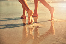 Bare Feet Of Women Walking On Wet Sand On Sunny Summer Beach