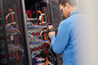 © Rafal Rodzoch/Caia Image - Male IT technician performing diagnostics on panel in server room