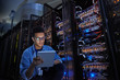 © Agnieszka Olek/Caia Image - Focused male IT technician using digital tablet in dark server room